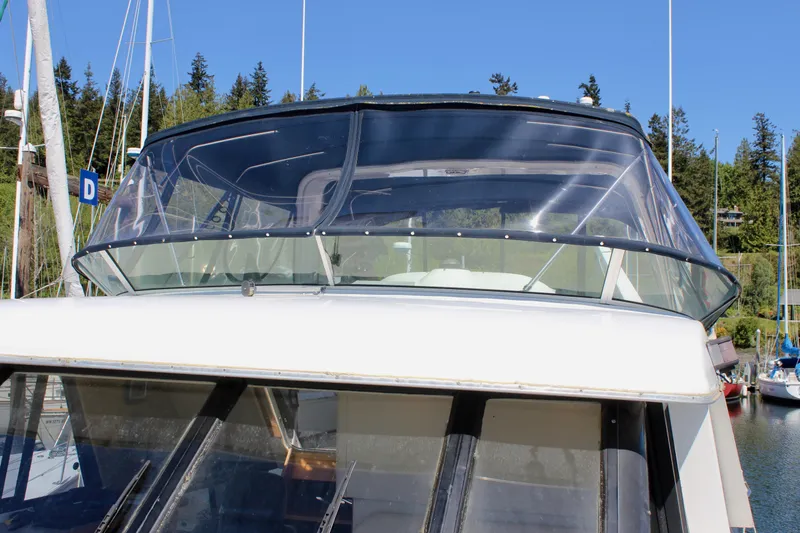 Slide: The Image of 1999 Bayliner 4788 Motoryacht with clear cockpit enclosure, docked in a marina. - 19