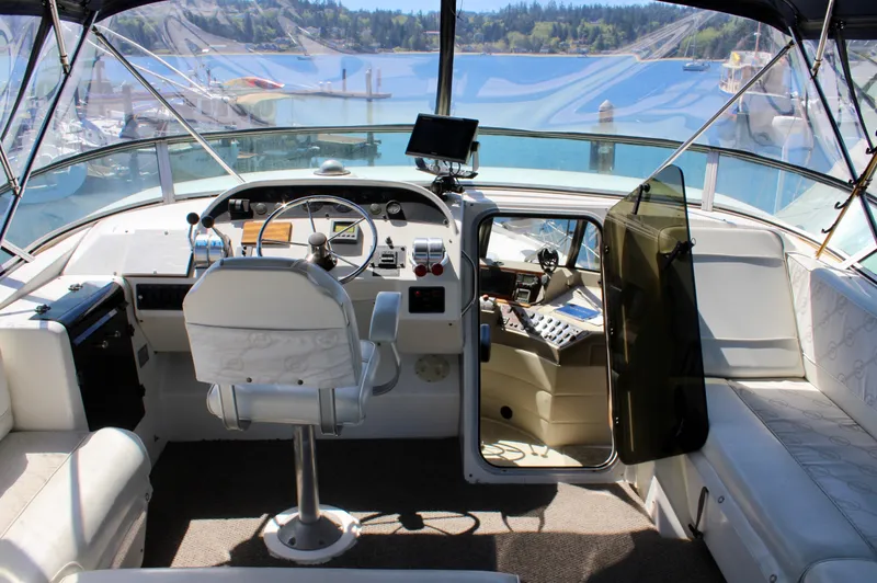 Slide: The Image of 1999 Bayliner 4788 Motoryacht helm with scenic marina view, featuring modern navigation equipment. - 26