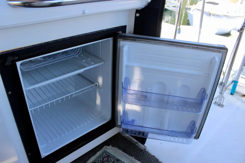 Slide: The Image of Open mini fridge on 1999 Bayliner 4788 Motoryacht, showing empty shelves and door storage. - 32