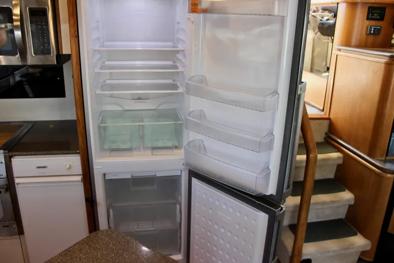Slide: The Image of Open refrigerator in 1999 Bayliner 4788 Motoryacht kitchen, showcasing spacious interior and adjacent stairs. - 43