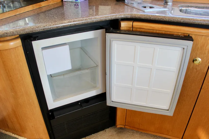 Slide: The Image of Open mini fridge in 1999 Bayliner 4788 Motoryacht kitchen with wooden cabinetry and countertop. - 47