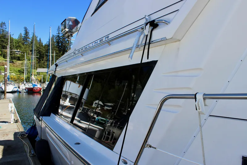 Slide: The Image of 1999 Bayliner 4788 Motoryacht docked at a marina, showcasing sleek design and windows. - 7
