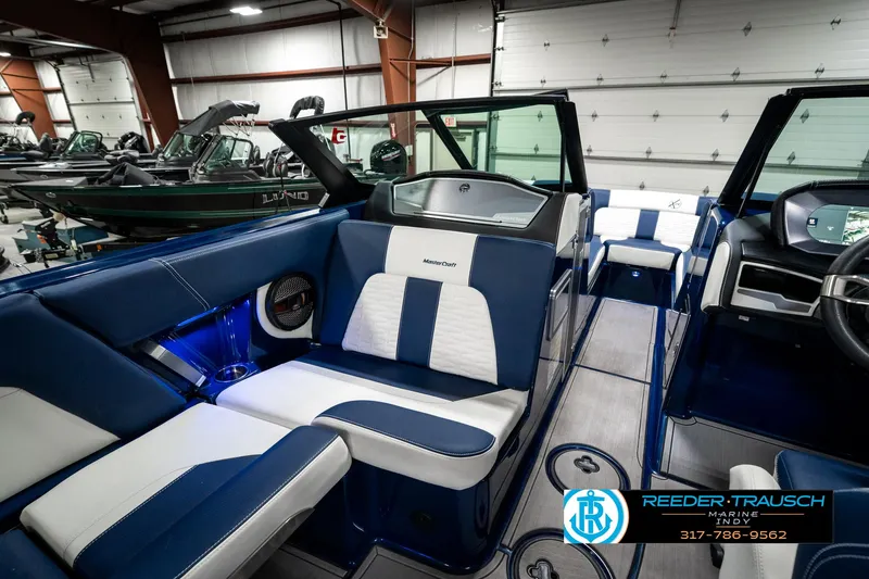 Slide: The Image of 2025 MasterCraft X24 boat interior with blue and white seating in a showroom. - 26