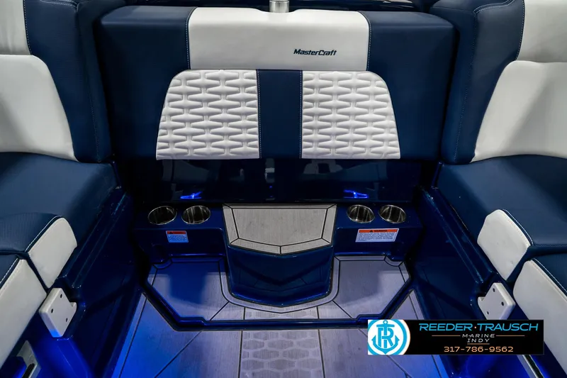 Slide: The Image of 2025 MasterCraft X24 interior with blue and white seating, cup holders, and ambient lighting. - 33