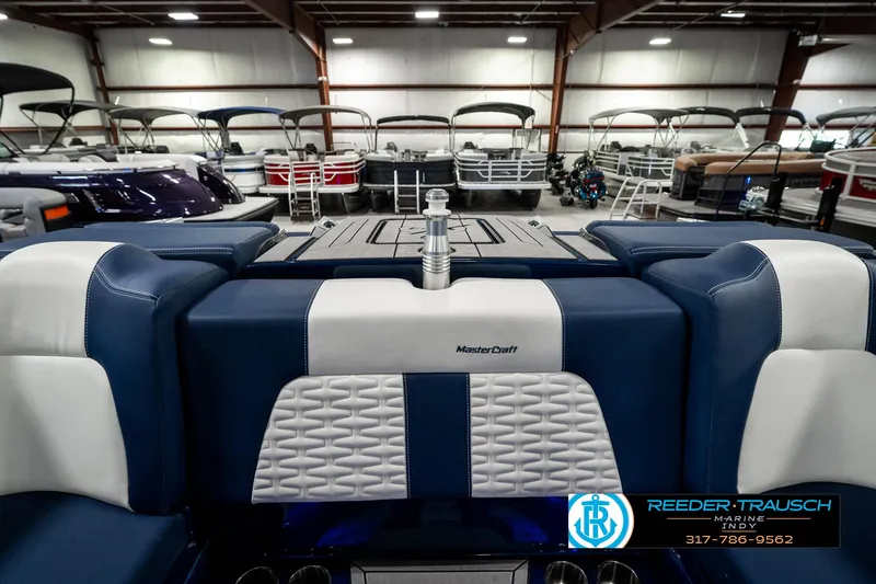 Slide: The Image of 2025 MasterCraft X24 boat interior in showroom, featuring blue and white seating. - 34