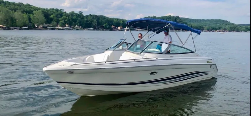 Slide: The Image of 2000 Formula 280 Bowrider boat cruising on a lake with two passengers under a blue canopy. - 1