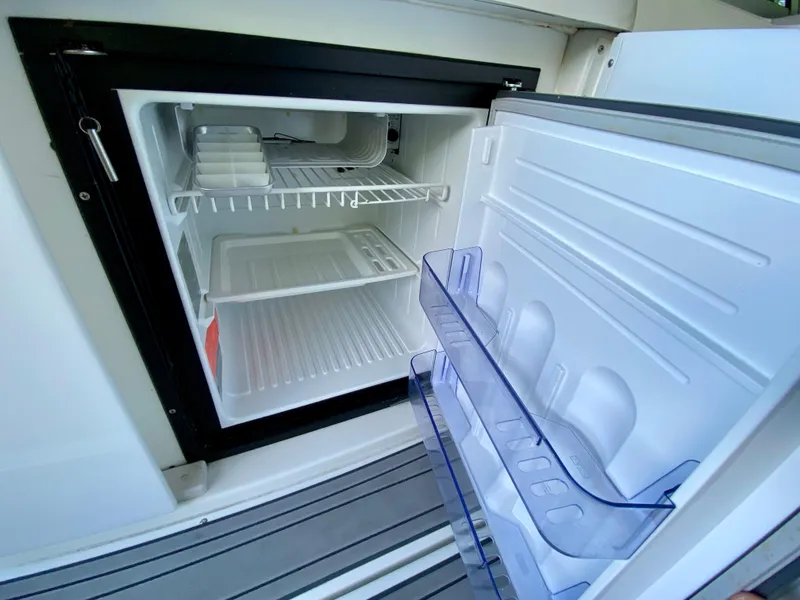 Slide: The Image of Open mini fridge on a 2000 Formula 280 Bowrider boat, showing empty shelves and door compartments. - 14