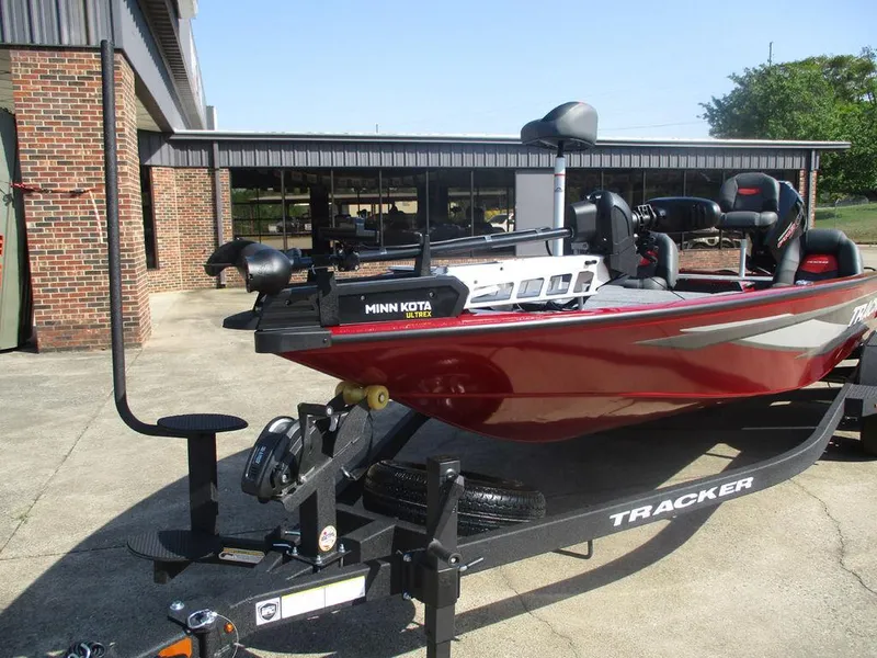 Slide: The Image of 2025 Tracker SAVAGE™ 215 boat on trailer, featuring Minn Kota trolling motor, parked outdoors. - 8
