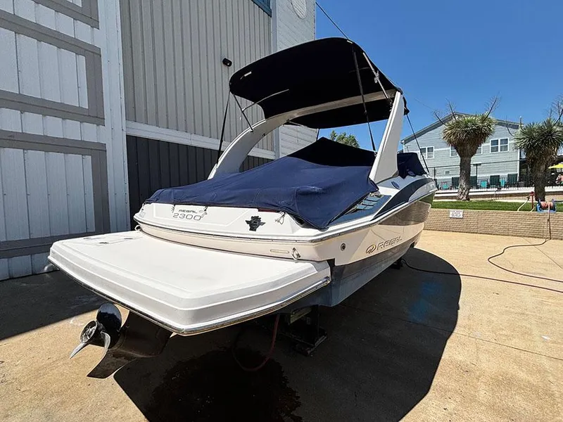Slide: The Image of 2010 Regal 2300 RX Bowrider boat with cover, parked outdoors on a sunny day. - 3