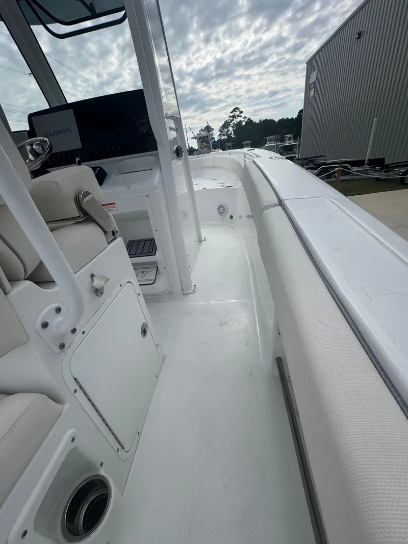 Slide: The Image of 2023 Sea Hunt Ultra 255 SE boat interior with seating and console, under a cloudy sky. - 19