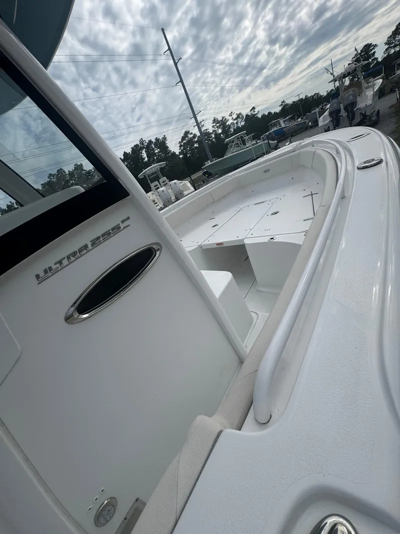 Slide: The Image of 2023 Sea Hunt Ultra 255 SE boat, showcasing sleek design and spacious deck under cloudy sky. - 20
