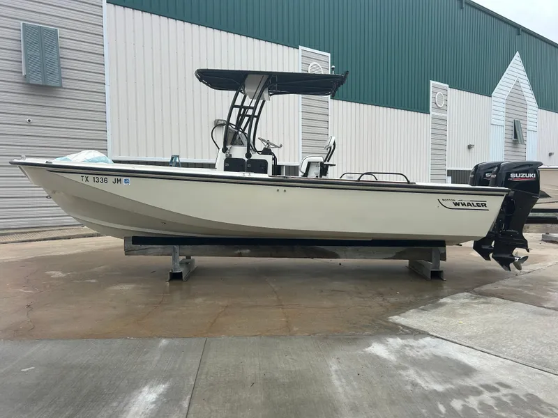 Slide: The Image of 1983 Boston Whaler 25 Outrage boat with Suzuki outboard motor, docked outdoors. - 1
