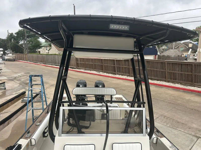 Slide: The Image of 1983 Boston Whaler 25 Outrage boat with T-top and dual engines, docked outdoors. - 18