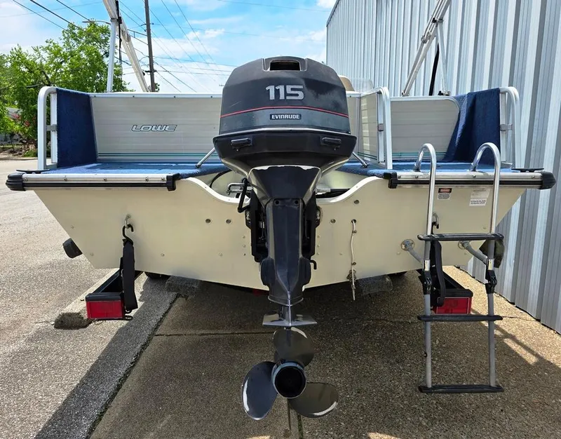Slide: The Image of 1997 Lowe LS 2220 boat with Evinrude 115 outboard motor, docked near a metal building. - 7