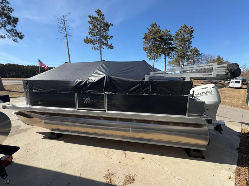 Slide: The Image of Custom Maui 160 Cruise pontoon boat, 2025 model, covered and parked outdoors. - 6