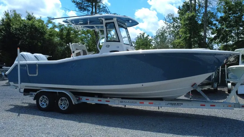 Slide: The Image of 2025 Tidewater 282 CC Adventure boat on trailer, blue hull, parked outdoors. - 10