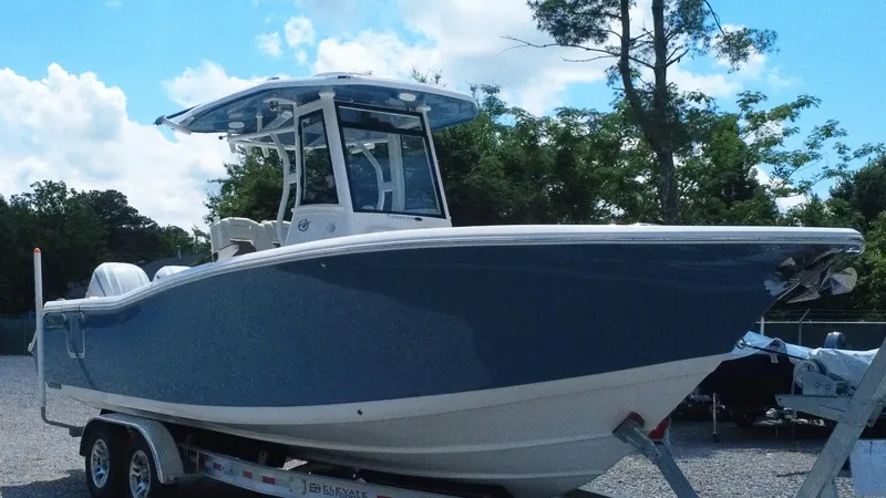 Slide: The Image of 2025 Tidewater 282 CC Adventure boat on trailer, parked outdoors under a blue sky. - 11