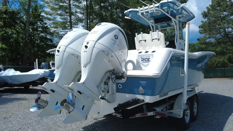 Slide: The Image of 2025 Tidewater 282 CC Adventure boat with dual engines on a trailer, parked outdoors. - 12