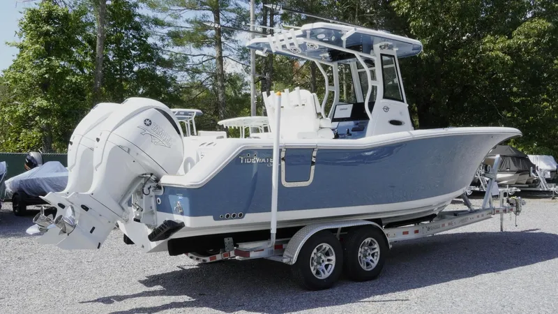 Slide: The Image of 2025 Tidewater 282 CC Adventure boat on trailer, featuring dual engines, parked outdoors. - 13