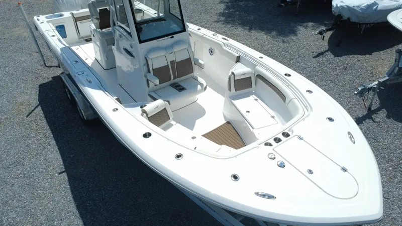 Slide: The Image of 2025 Tidewater 282 CC Adventure boat, white exterior, spacious deck, dual console, parked on gravel. - 8