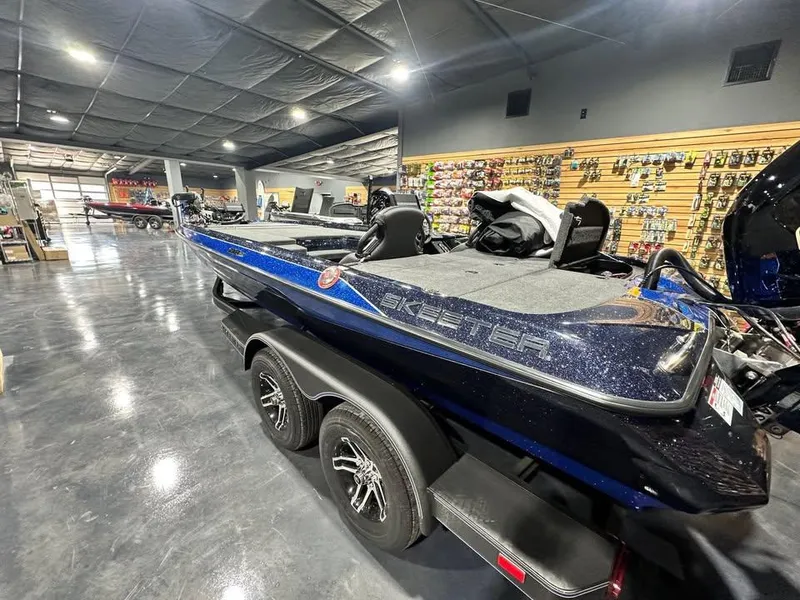 Slide: The Image of 2025 Skeeter ZXR21 boat in showroom, sleek design, dual axle trailer, fishing gear displayed. - 3