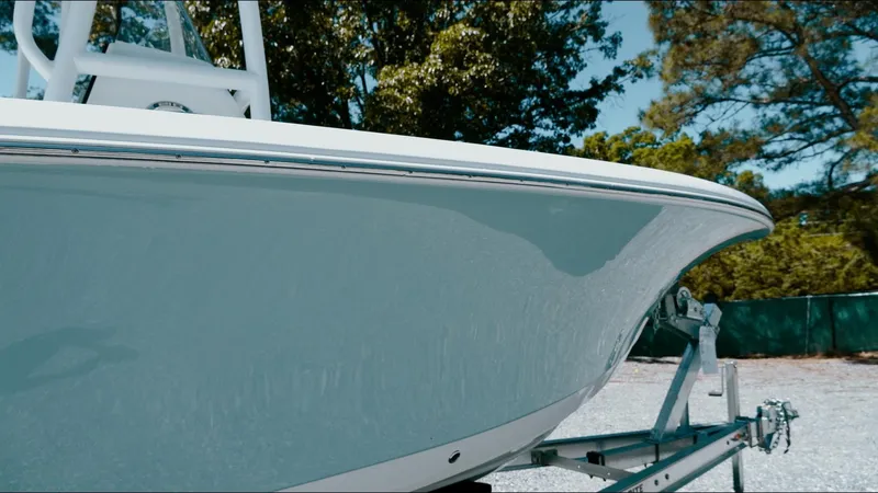 Slide: The Image of 2025 Tidewater 210 LXF boat on trailer, side view, outdoors with trees in background. - 19