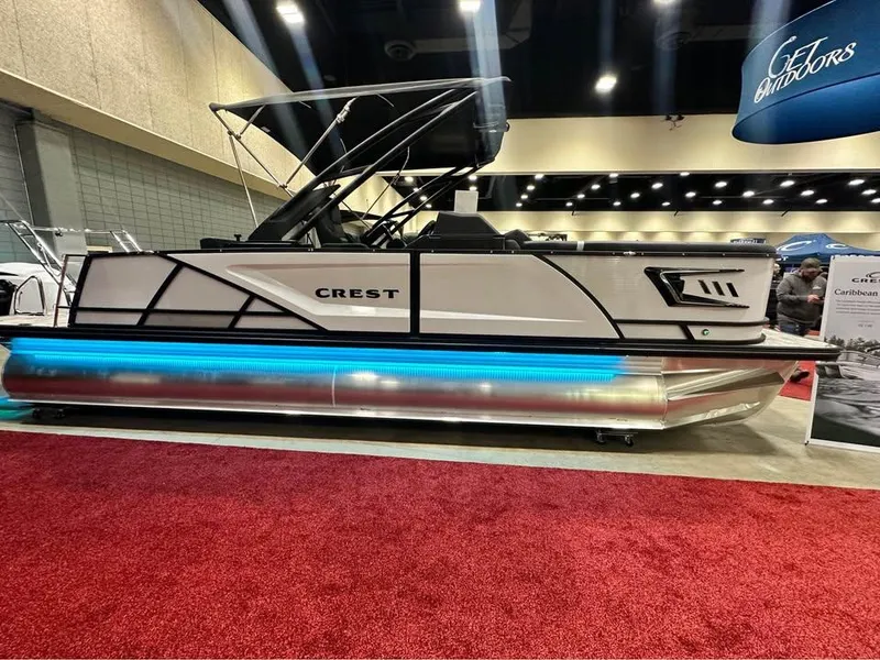 Slide: The Image of 2025 Crest Caribbean RS 230 pontoon boat displayed indoors on red carpet. - 3