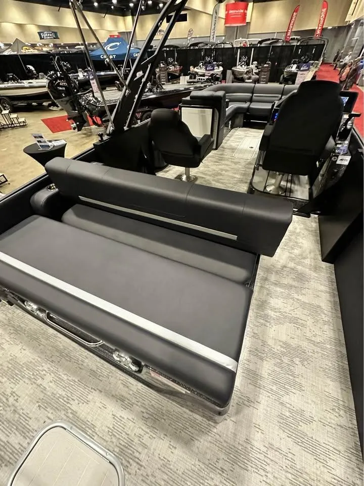 Slide: The Image of 2025 Crest Caribbean RS 230 pontoon boat interior with luxurious seating at a boat show. - 5