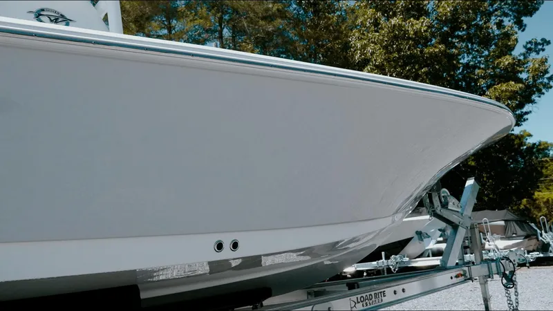 Slide: The Image of 2025 Tidewater 2210 Carolina Bay boat on trailer, side view with trees in background. - 15