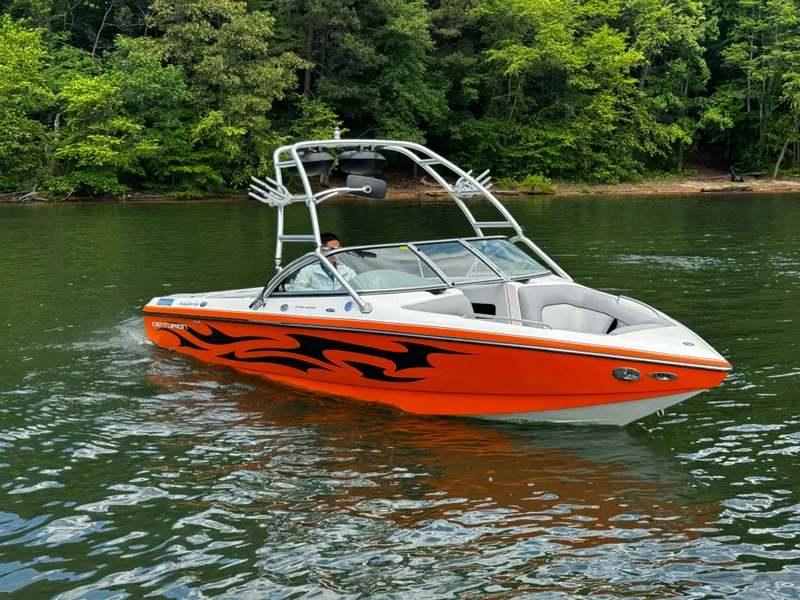 Slide: The Image of 2007 Centurion Avalanche boat with orange flame design on a lake, surrounded by trees. - 1