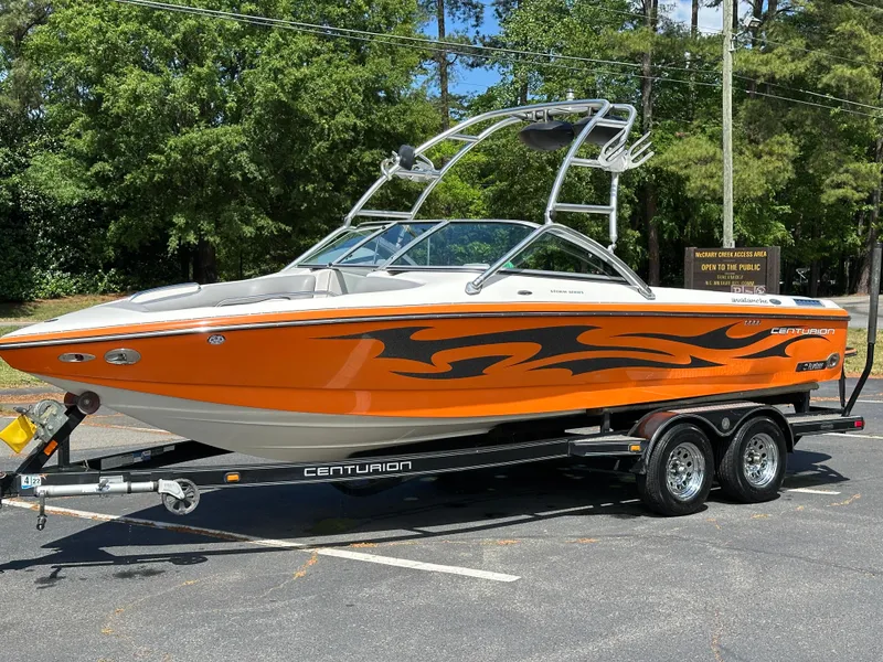 Slide: The Image of 2007 Centurion Avalanche boat with orange and black design on a trailer, parked outdoors. - 20