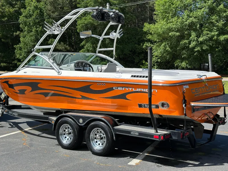 Slide: The Image of 2007 Centurion Avalanche boat with orange and black design on a trailer, parked outdoors. - 22