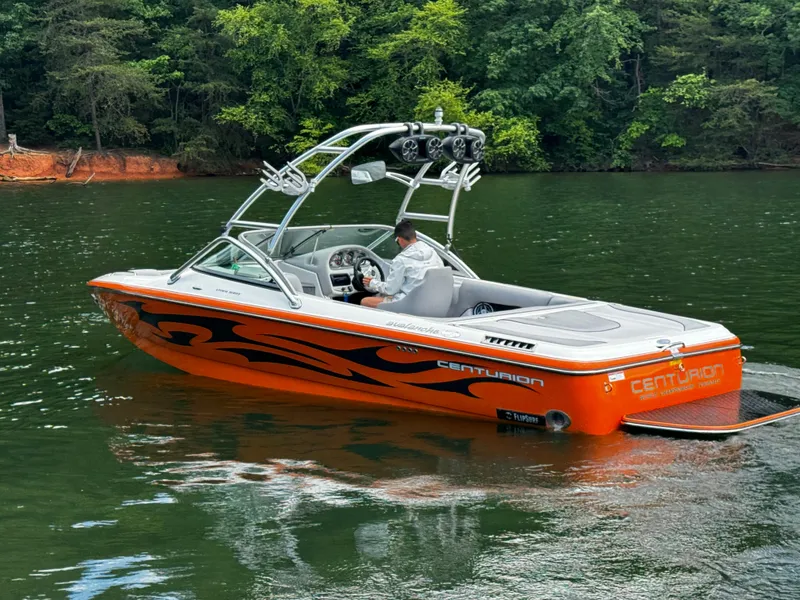 Slide: The Image of 2007 Centurion Avalanche boat on a lake, vibrant orange with black graphics, surrounded by trees. - 7