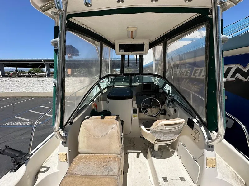 Slide: The Image of 2002 Trophy Walkaround boat interior with steering wheel and seating, docked under clear blue sky. - 14
