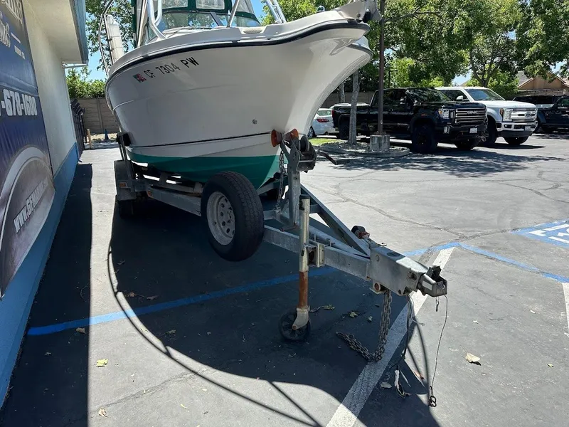 Slide: The Image of 2002 Trophy Walkaround boat on trailer in parking lot, surrounded by trees and vehicles. - 3