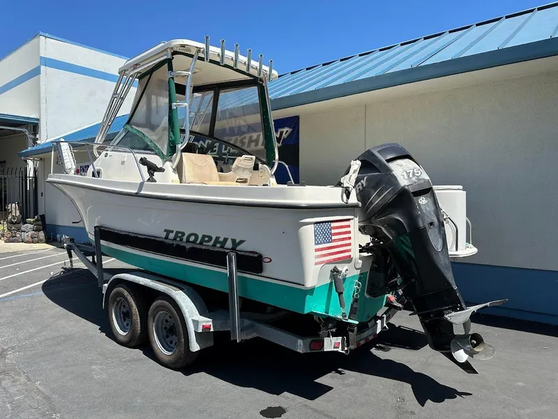 Slide: The Image of 2002 Trophy Walkaround boat on trailer, parked outdoors, featuring outboard motor and American flag decal. - 7