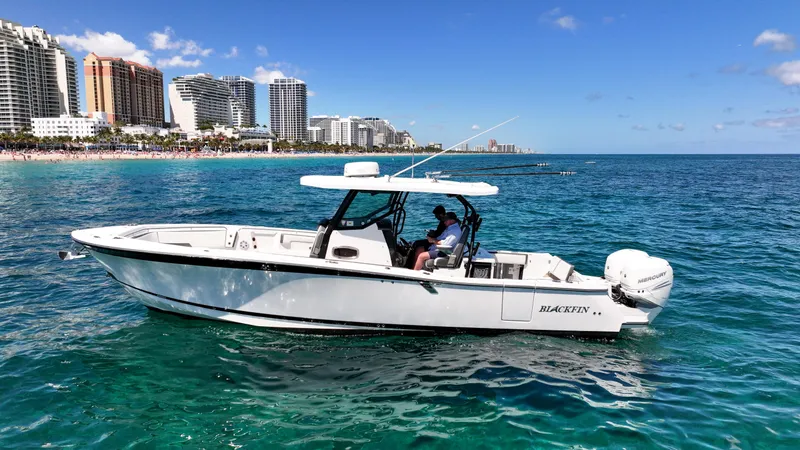 Slide: The Image of 2020 Blackfin 332 CC boat cruising near a city shoreline under a clear blue sky. - 4