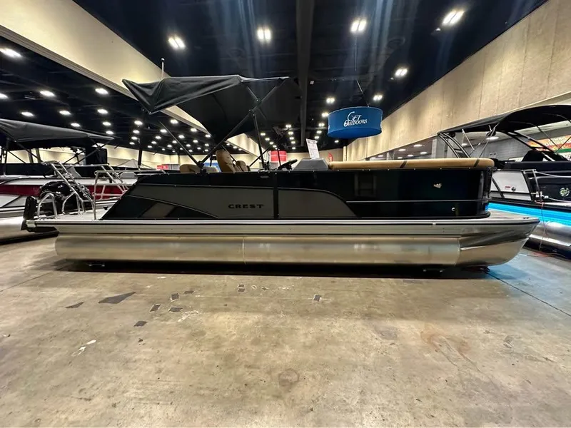 Slide: The Image of 2025 Crest Classic 240 pontoon boat displayed indoors with canopy and sleek design. - 1