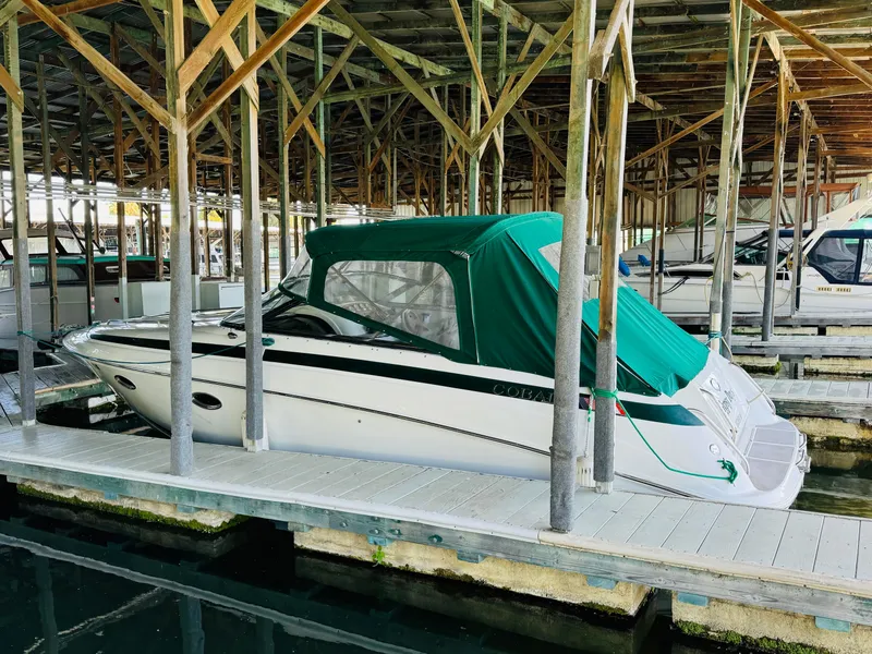 Slide: The Image of 1998 Cobalt 293 boat with green canopy docked in a covered marina. - 4