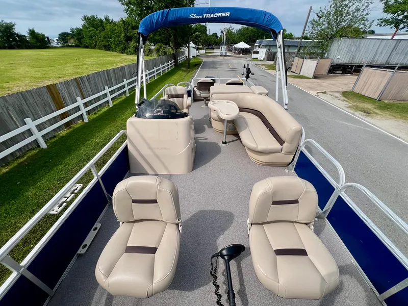Slide: The Image of 2017 Sun Tracker Fishin' Barge 22 DLX pontoon boat with beige seating and blue canopy. - 17