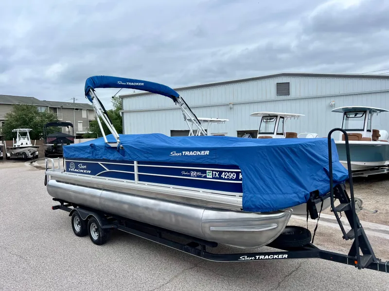 Slide: The Image of 2017 Sun Tracker Fishin' Barge 22 DLX pontoon boat with blue cover on trailer. - 24