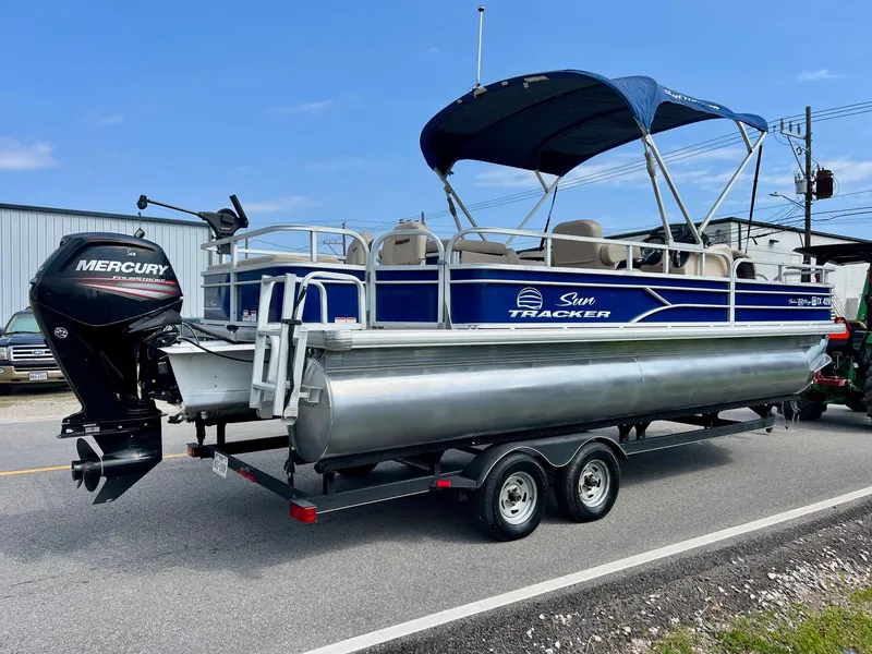 Slide: The Image of 2017 Sun Tracker Fishin' Barge 22 DLX pontoon boat on trailer, with Mercury outboard motor. - 4