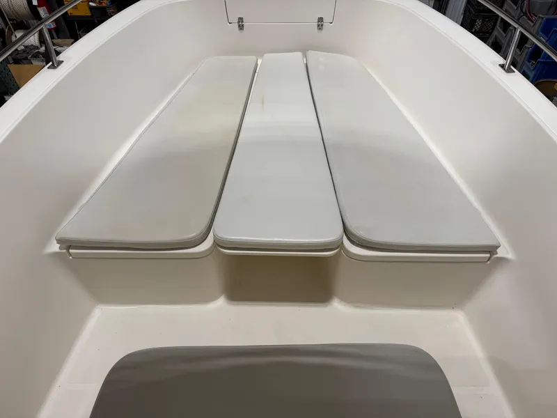 Slide: The Image of 2004 Pursuit 2470 CC boat interior with cushioned seating and clean white deck. - 13