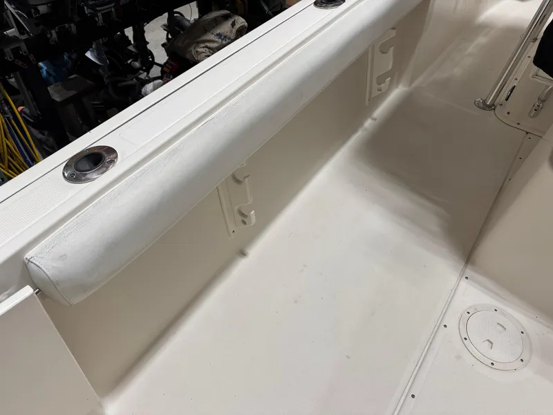 Slide: The Image of 2004 Pursuit 2470 CC boat interior, featuring clean white deck and rod holders. - 16