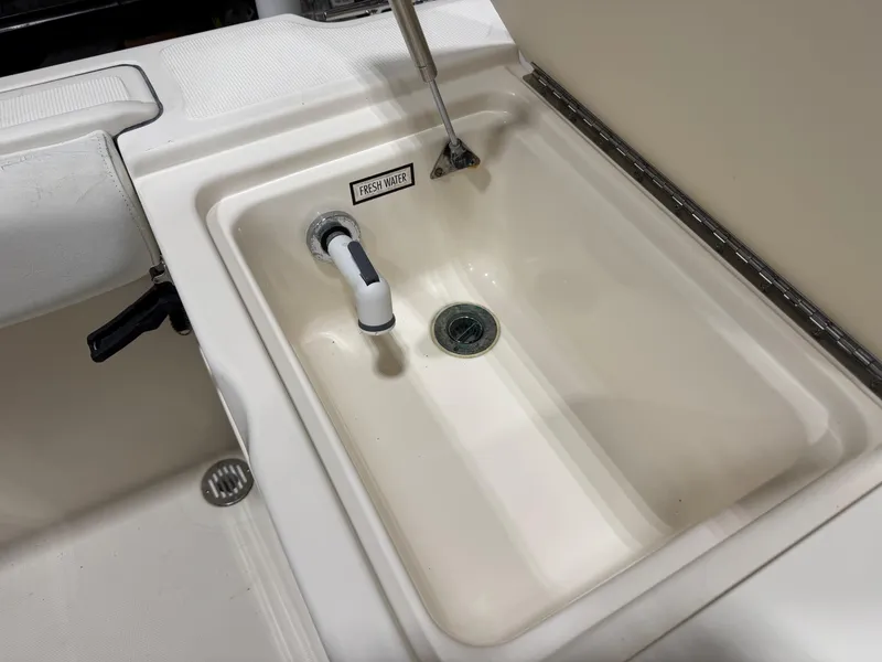 Slide: The Image of Freshwater sink on a 2004 Pursuit 2470 CC boat, featuring a white basin and faucet. - 21