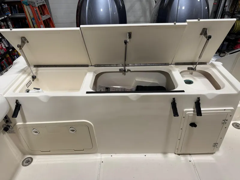 Slide: The Image of 2004 Pursuit 2470 CC boat storage compartments with open lids, showcasing interior features. - 22