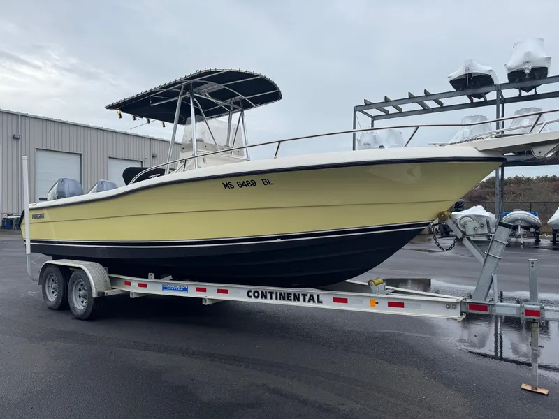 Slide: The Image of 2004 Pursuit 2470 CC boat on a Continental trailer in a marina setting. - 3