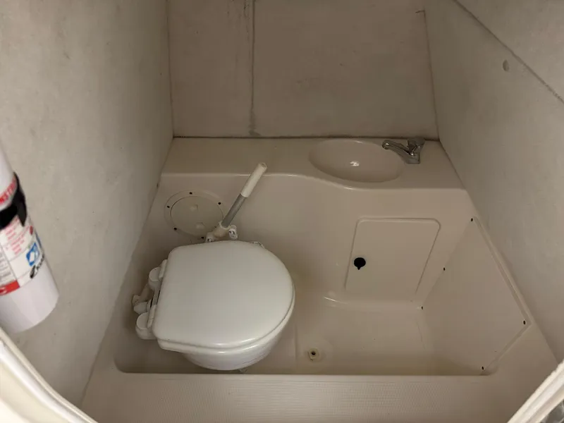 Slide: The Image of 2004 Pursuit 2470 CC boat bathroom with toilet, sink, and fire extinguisher. - 33