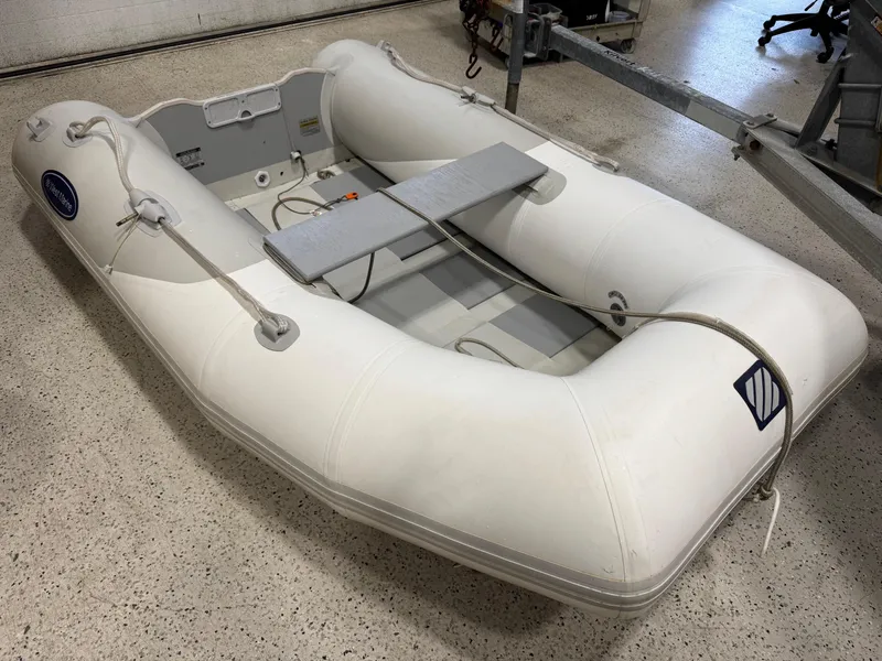 Slide: The Image of 2004 Pursuit 2470 CC inflatable boat on a speckled floor in a garage setting. - 34