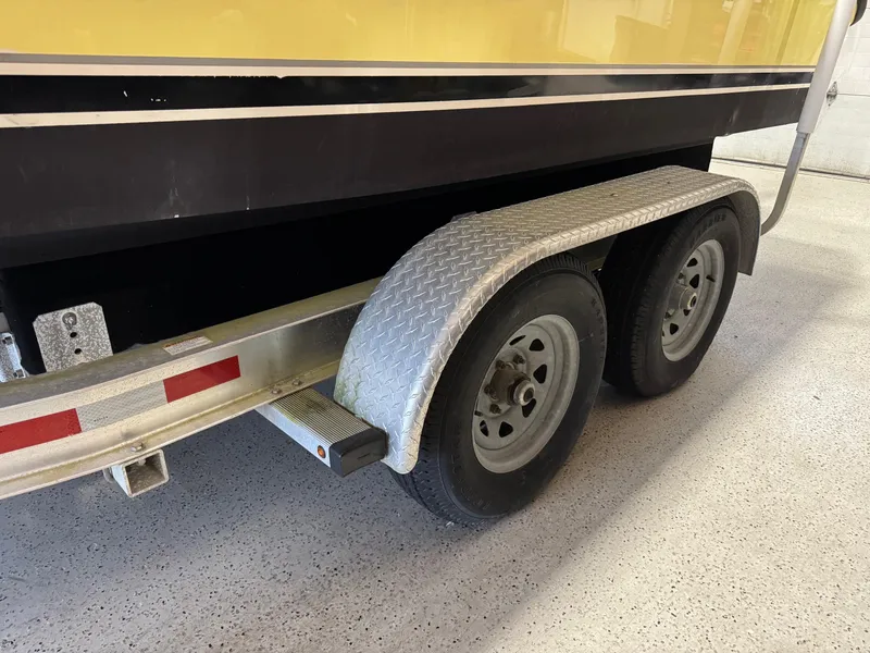 Slide: The Image of Trailer with dual wheels for 2004 Pursuit 2470 CC boat, in a garage setting. - 37